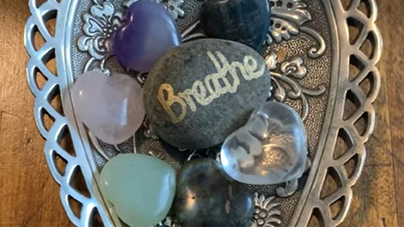 A bowl of crystals and a rock that says breathe